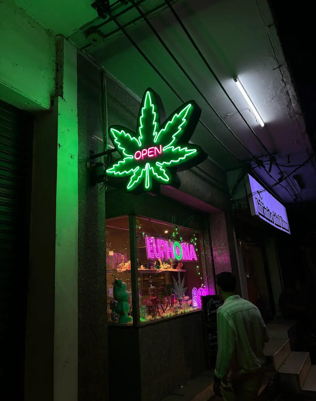Illuminated cannabis leaf OPEN sign outside Euphoria dispensary on Decho Road, Bangkok